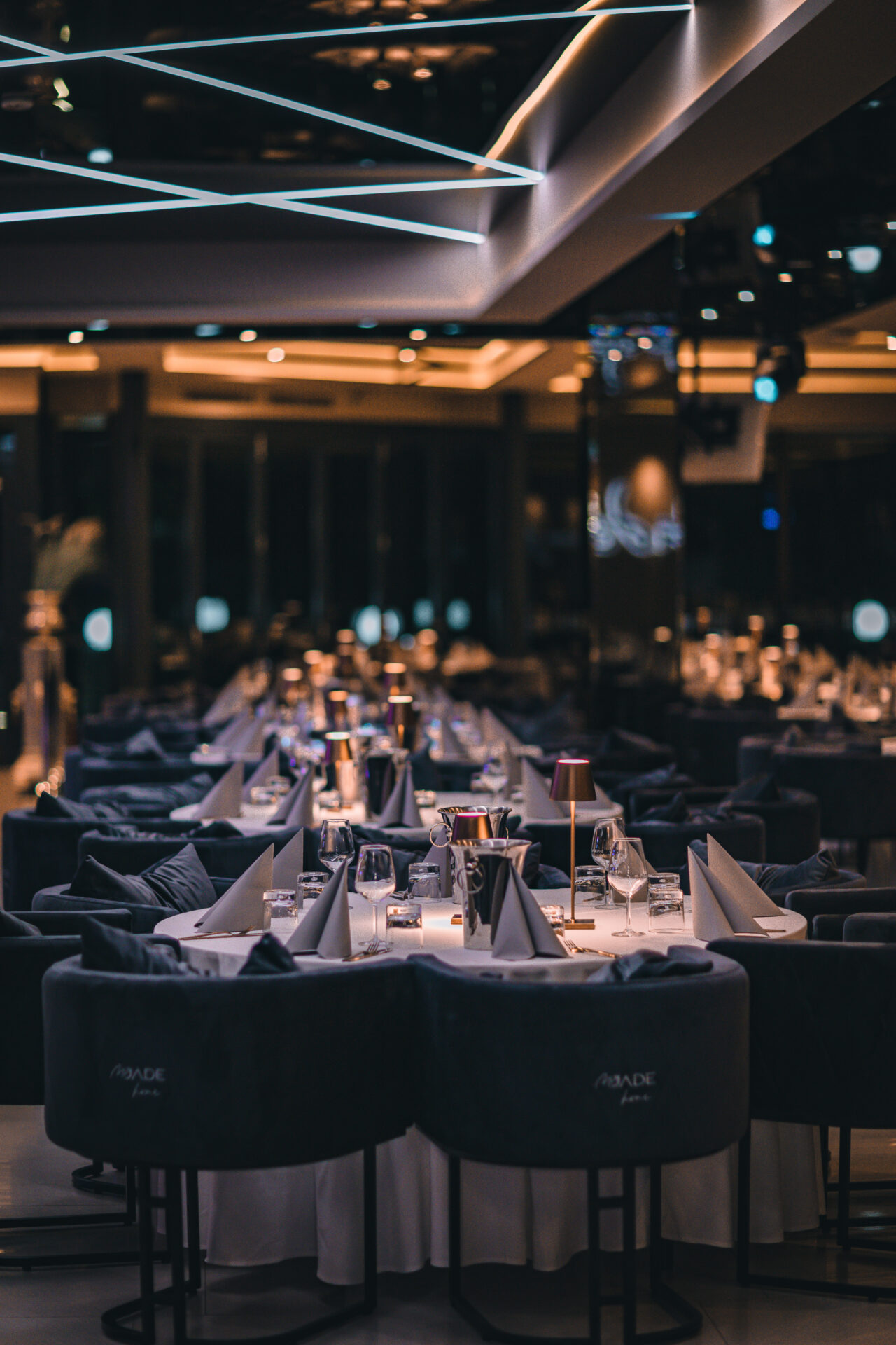 Tischreihen in elegantem Setting mit Gläsern, Servietten und Leuchten