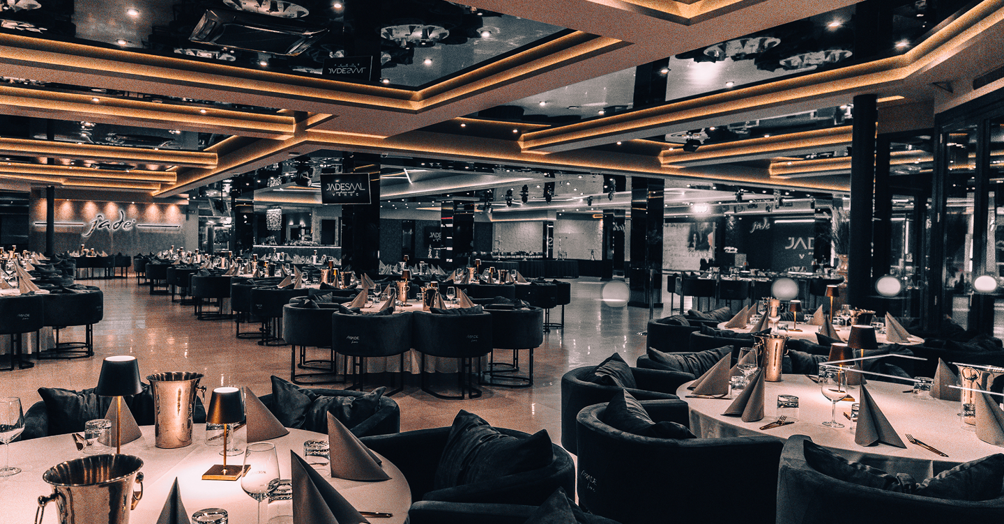 Edler Innenraum der Eventlocation MR JADE mit elegant gedeckten runden Tischen und warmem Licht