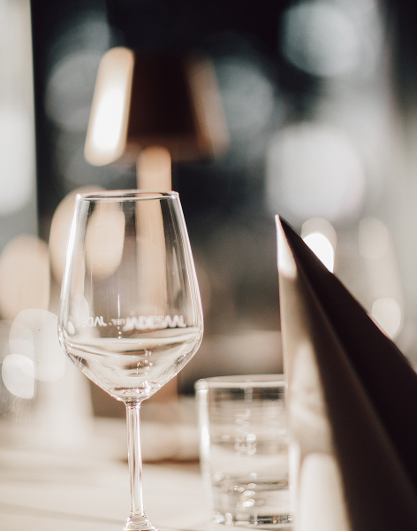 Detailaufnahme eines Weinglases mit MR JADE Logo, stilvolle Beleuchtung im Hintergrund